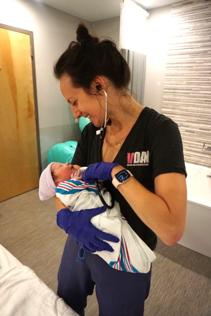 Smiling-midwife-holding-newborn-baby-at-a-birth-center