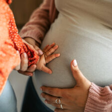 Cute Baby Girl Touching Pregnant Belly of her Mother