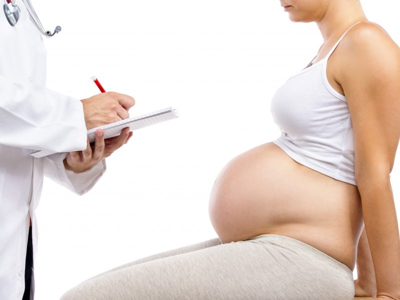 Doctor taking notes talking to pregnant woman