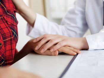 Close up view of female doctor touching patient hand for encouragement
