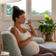 Pregnant-woman-drinking-water-on-sofa