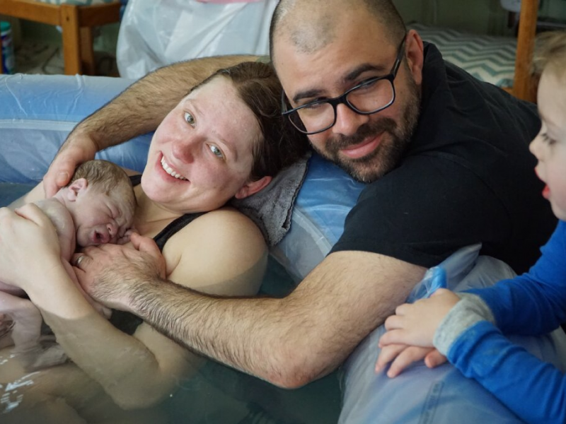 joyful new parents with newborn born into waterbirth tub