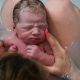 newborn on mom's knees in waterbirth tub midwifery care